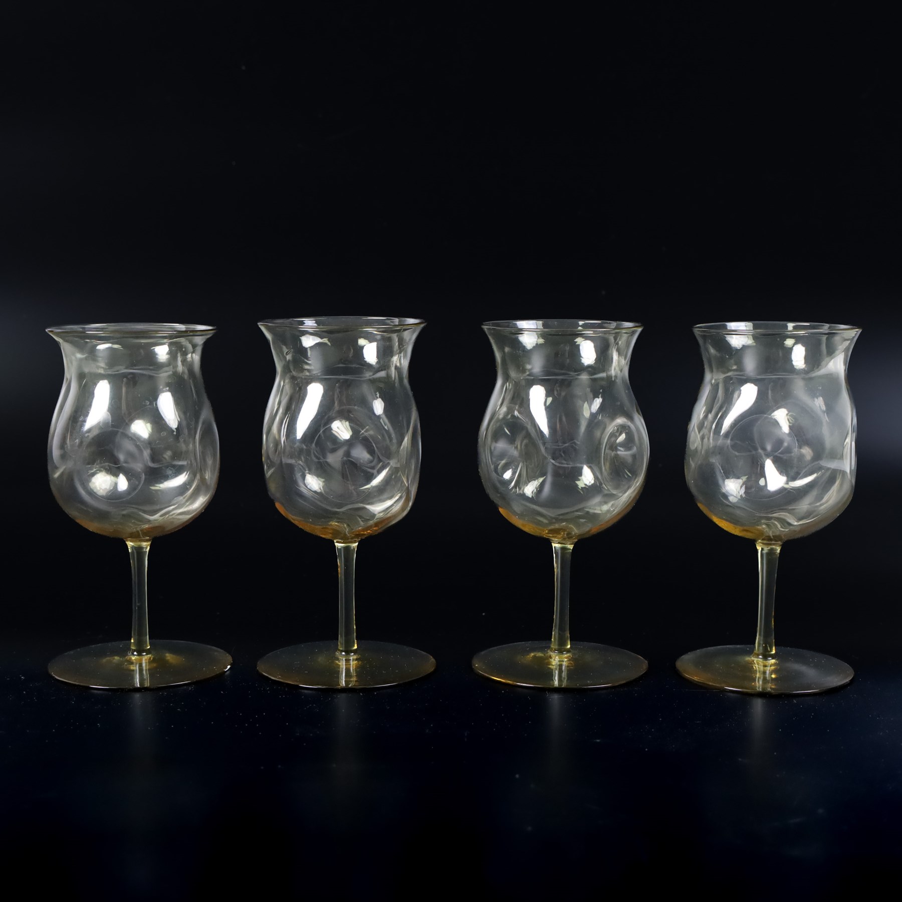 Four Arts and Crafts drinking glasses of dimple form, probably James Powell, Whitefriars, together with a dimple decanter, glasses H12cm