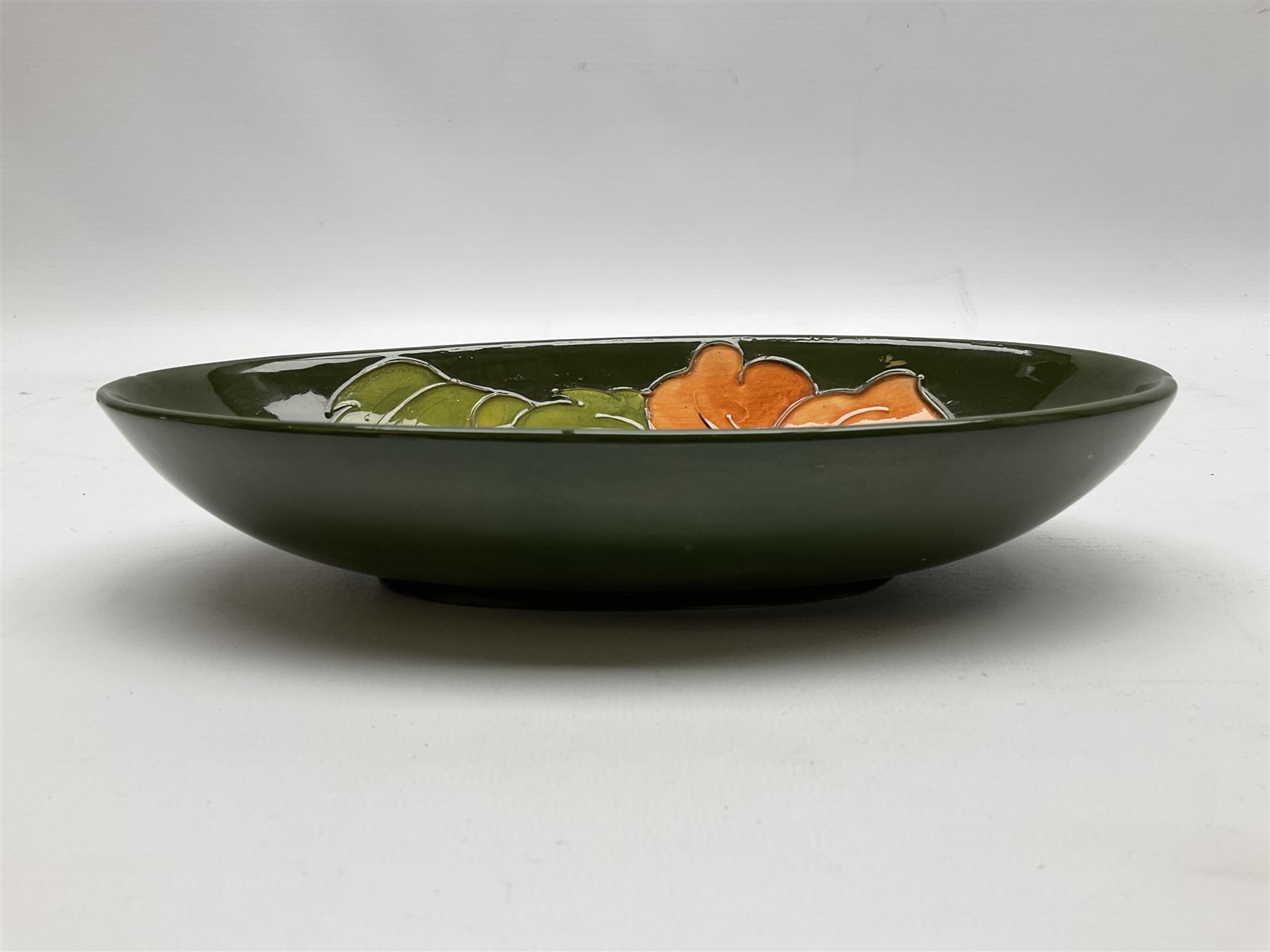 Moorcroft oval bowl, decorated in the Hibiscus pattern upon a green