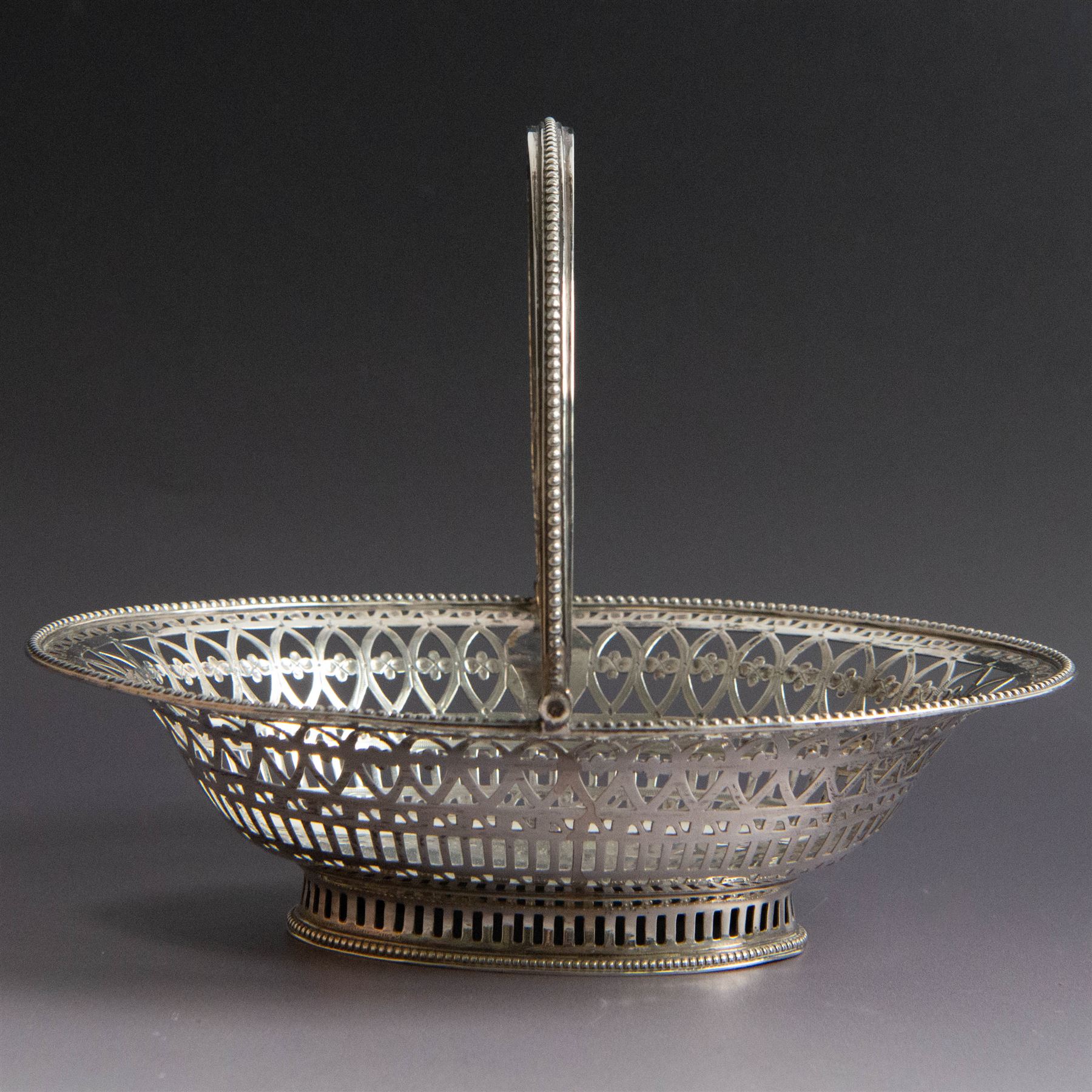 George III silver bon bon basket, of oval form with bead rim and swing handle, the sides with pierced latticework decoration, hallmarked Hester Bateman, London 1785, handle H14cm