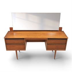 Austinsuite - mid 20th century teak headboard with bedside cabinets and matching  mirrored dressing table, the headboard with floating single drawer bedsides raised on a single tapering support, the dressing table with attached tilting mirror, above rectangular top with kneehole and two banks of two drawers, raised on tapering supports

Headboard H 84cm, D 40cm, W 229cm, W between bedsides 151cm 
Dressing table H 113cm D 44cm, W 149cm, H to underside of dresser 61cm