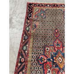 Persian Hamadan rug, the rosette pole medallion on a pale field decorated with stylised motifs, the blue band border decorated with stylised flower heads