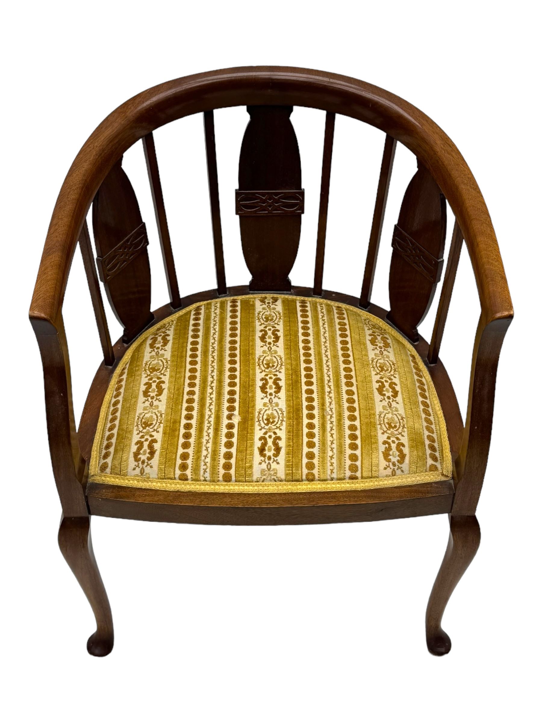 Late Victorian mahogany framed tub chair, rounded backrest with vertical splats and three carved oval medallions, upholstered seat in yellow patterned fabric, on cabriole supports