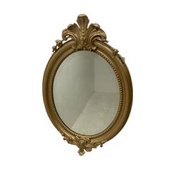 Victorian wall mirror, in oval moulded frame mounted by carved cartouches, bevelled glass plate