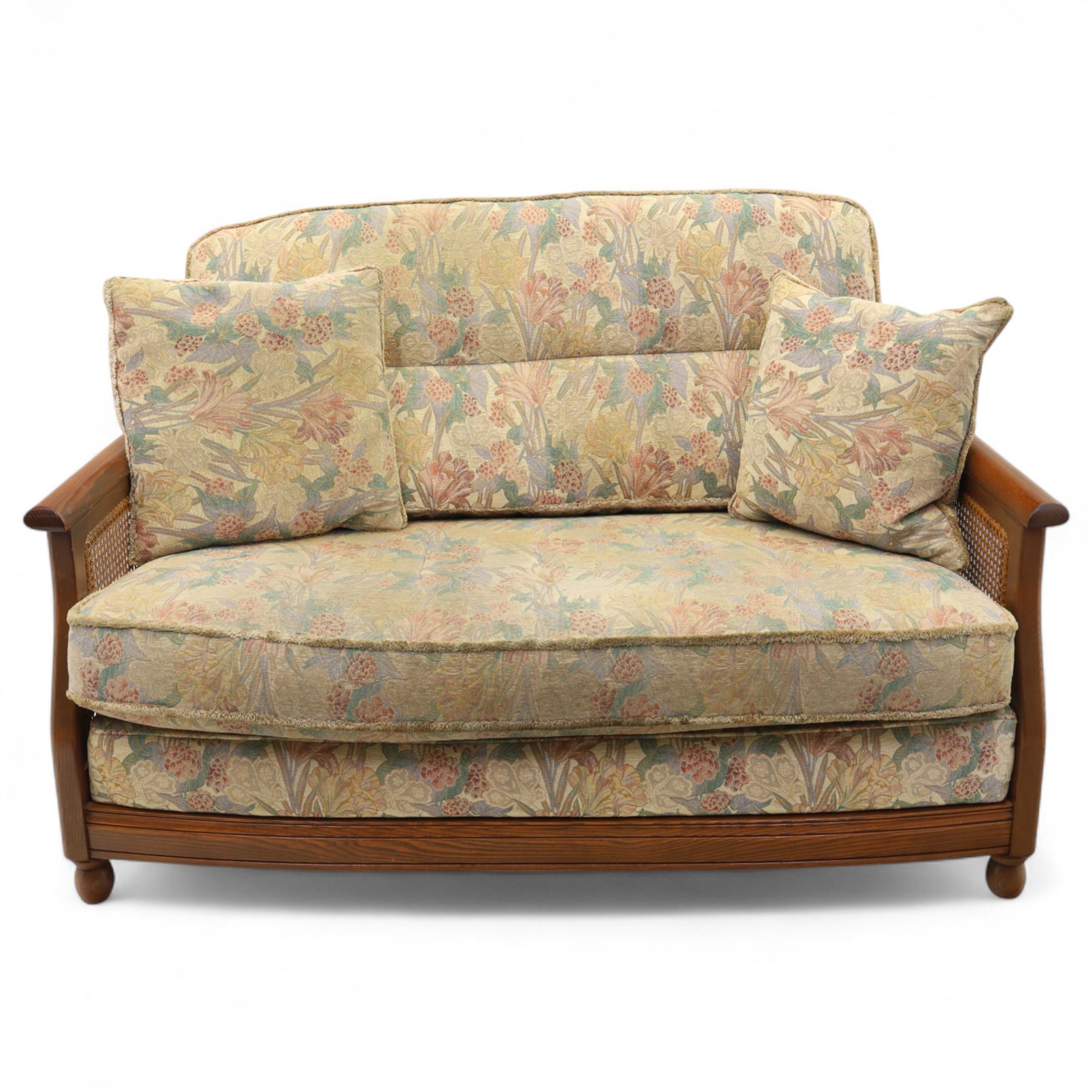 Ercol – bergère four piece suite, including armchair, two seat sofa, three seat sofa and footstool, all with removable floral upholstered cushions, the frames with side caning and rounded arm supports in stained beech

Three seat (H 87cm, D 89cm, W 196cm)
Two seat (H 87cm, D 89cm, W 137cm)
Armchair (H 87cm, D 89cm, W 87cm)
Footstool (H 28cm, D 55cm, W 55cm)