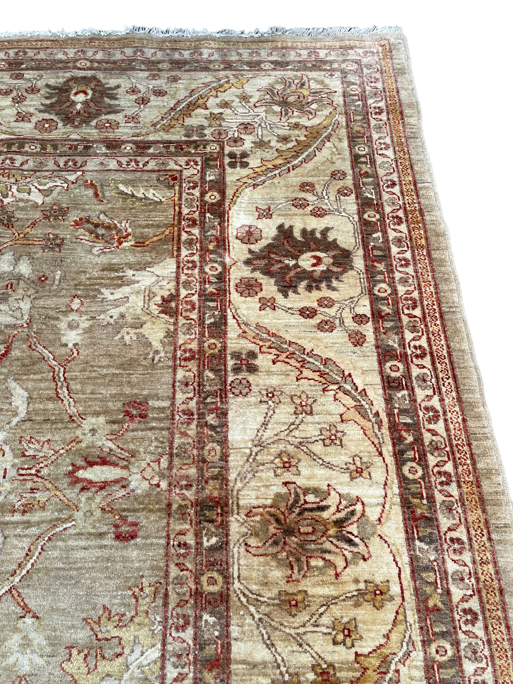 Pakistani ivory ground carpet, the field decorated with leaf branches, lotus flowers and roses, wide guarded border long leaves and stylised plant motifs