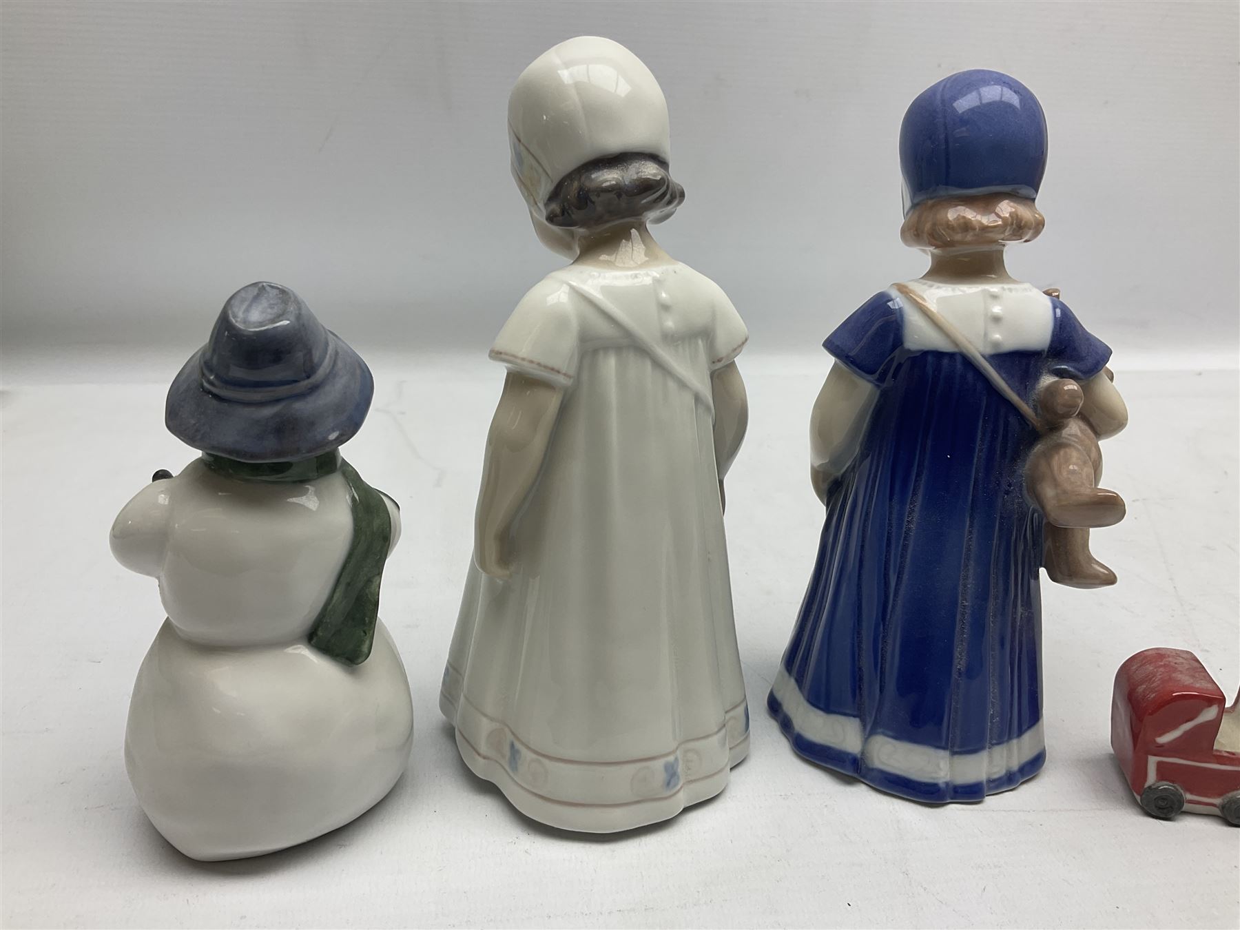 Four Royal Copenhagen figures, comprising Else with teddy no. 671, Snowman no. 158, Elsa no. 404, an mini collection girl with pram no.014, all with mark beneath  