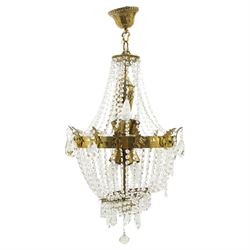 Empire design brass and crystal chandelier, the two circular brass tiers with foliate moun...