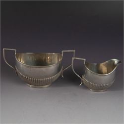 Early 20th century silver milk jug and open sucrier, each of oval part fluted form, hallma...
