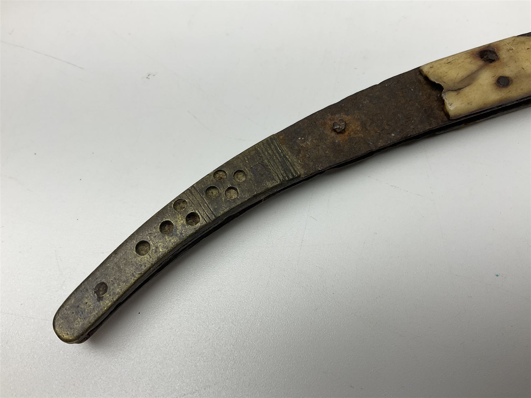 19th century continental folding knife with 15.5cm single edged blade, the pierced brass and iron handle with remains of horn grips L21.5cm overall closed; turned horn handled knife with foliate engraved blade; battlefield relic German 1884/98 knife bayonet; iron spear head; leather covered swagger stick; and two-piece gun cleaning rod