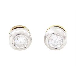 Pair of 18ct white and yellow gold diamond earrings, each stud bezel set with a round bril...