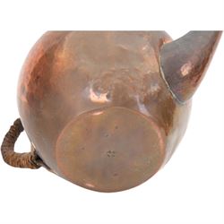Keswick School of Industrial Arts: Arts & Crafts copper teapot, of stylised squat form with cane bound reed handle and ebony finial, together with a lidded jug, of bellied form with cane bound handle and Bakelite type thumbpiece and a cream jug of squat form with stylised loop handle, all stamped KSIA beneath, tallest H14cm
