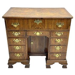 Early 18th century Queen Anne figured walnut kneehole desk with secretaire drawer, moulded and book matched top with walnut band, the top drawer with fall front enclosing small drawers and pigeon holes, fitted with nine drawers and central recessed cupboard, on ogee bracket feet