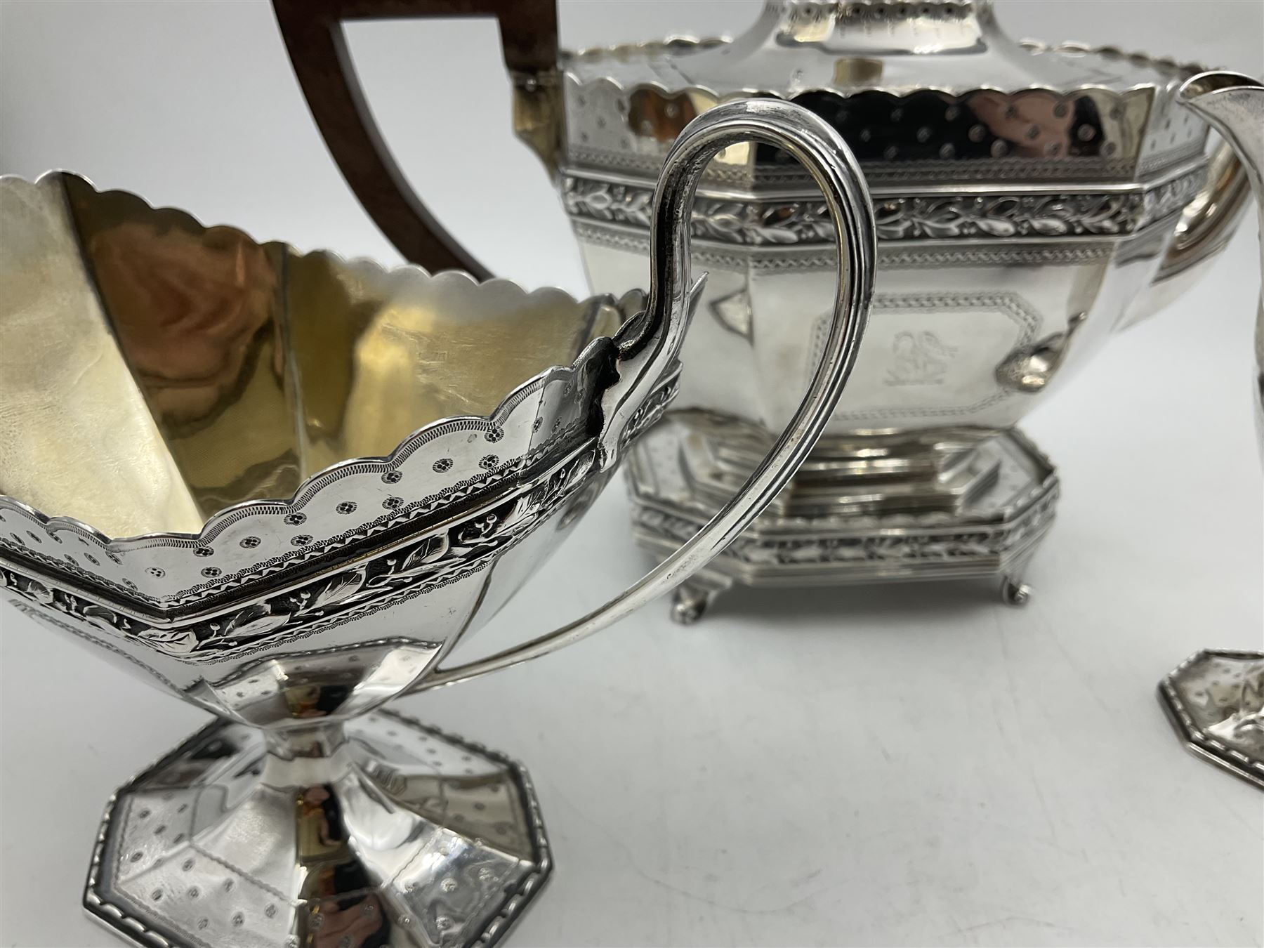 Victorian silver four piece tea service, comprising teapot, teapot stand, twin handled open sucrier and milk jug, each of octagonal form with foliate bud border and engraved decoration including crest to canted panels, and vacant panels, the teapot with ivory finial to the hinged cover and later wooden handle, hallmarked Edward Barnard & Sons Ltd, London1896, teapot including finial H15cm, milk jug including handle H16cm, teapot stand W11.5cm

This item has been registered for sale under Section 10 of the APHA Ivory Act