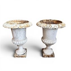 Pair of Victorian revival cast iron garden urns, egg and dart rim, tapering column with gadrooned waist, on square base, finished in distressed white paint