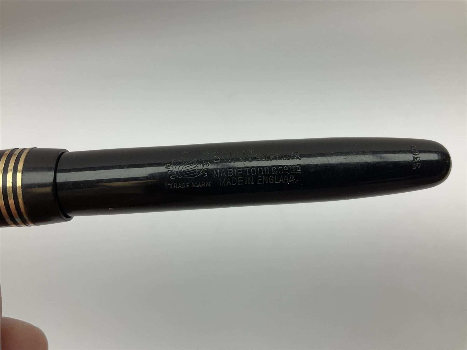 Vintage Swan Mabie Todd lever fill fountain pen in coral red, the nib a/f marked 14K, together with two further vintage Swan Mabie Todd fountain pens, the first example with lever fill, the other leverless, each with black body, one with nib marked 14ct, (3) 