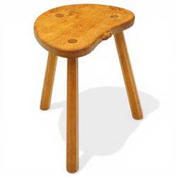 Mouseman - oak three-legged stool, dished kidney-shaped seat with burr inclusions, raised on three octagonal splayed supports, with carved mouse signature, by the workshop of Robert Thompson of Kilburn