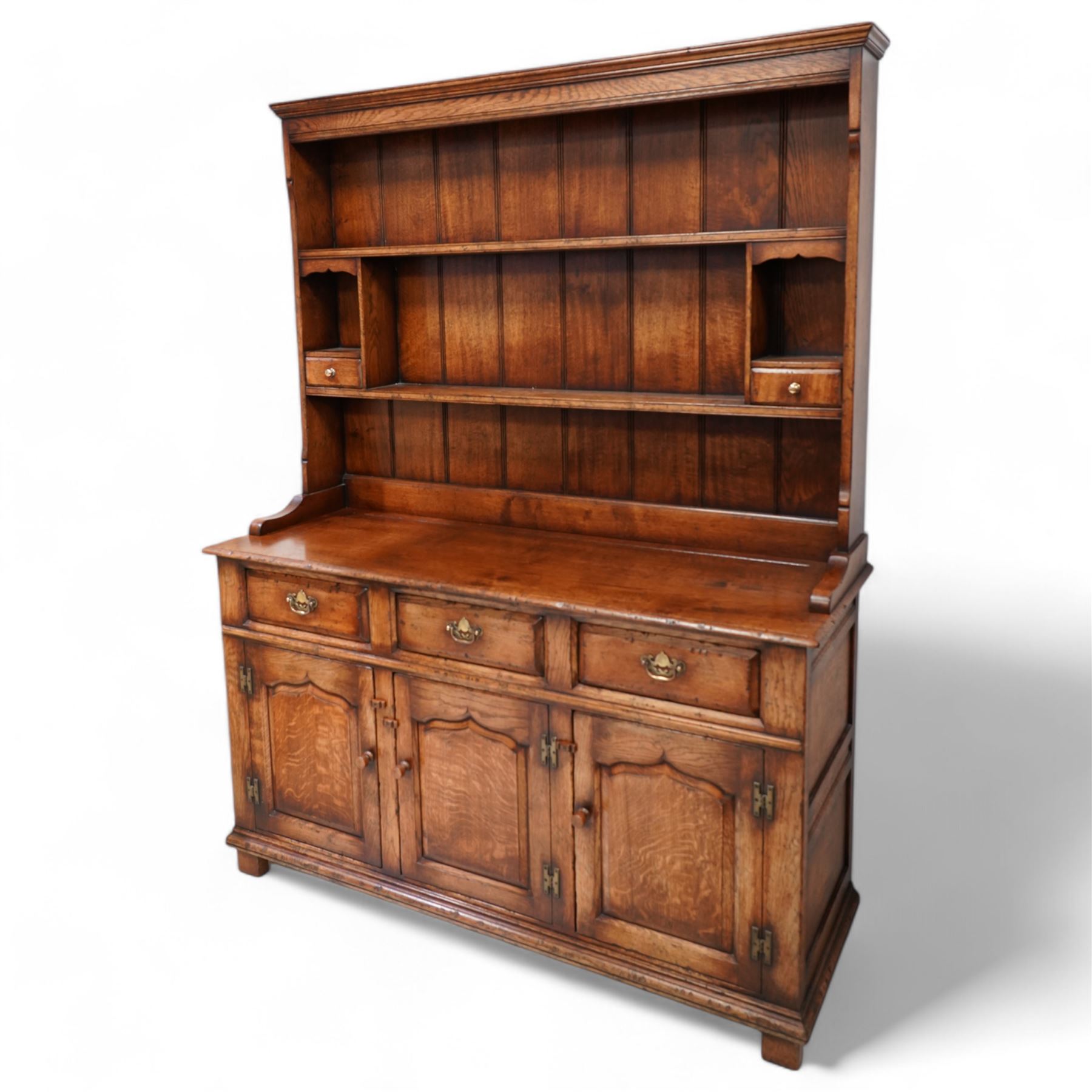 18th century design oak dresser, moulded cornice over two heights plate rack and two small drawers, the dresser base with moulded rectangular top over three drawers and three cupboards, enclosed by ogee arch panelled doors, on stile supports with applied lower moulding