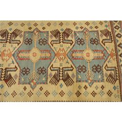 Two Caucasian designed rugs comprising a flatweave and hand-knotted rug, Caucasian design flatweave, cream ground with three large blue geometric medallions surrounded by stylised birds and geometric motifs, enclosed by repeating geometric border, fringed ends, H176cm, W102cm; hand-knotted Caucasian rug, ivory ground with three polychrome octagonal medallions surrounded by stylised animals, flowerheads and geometric motifs, enclosed by salmon pink geometric border, fringed ends, H163cm, W106cm