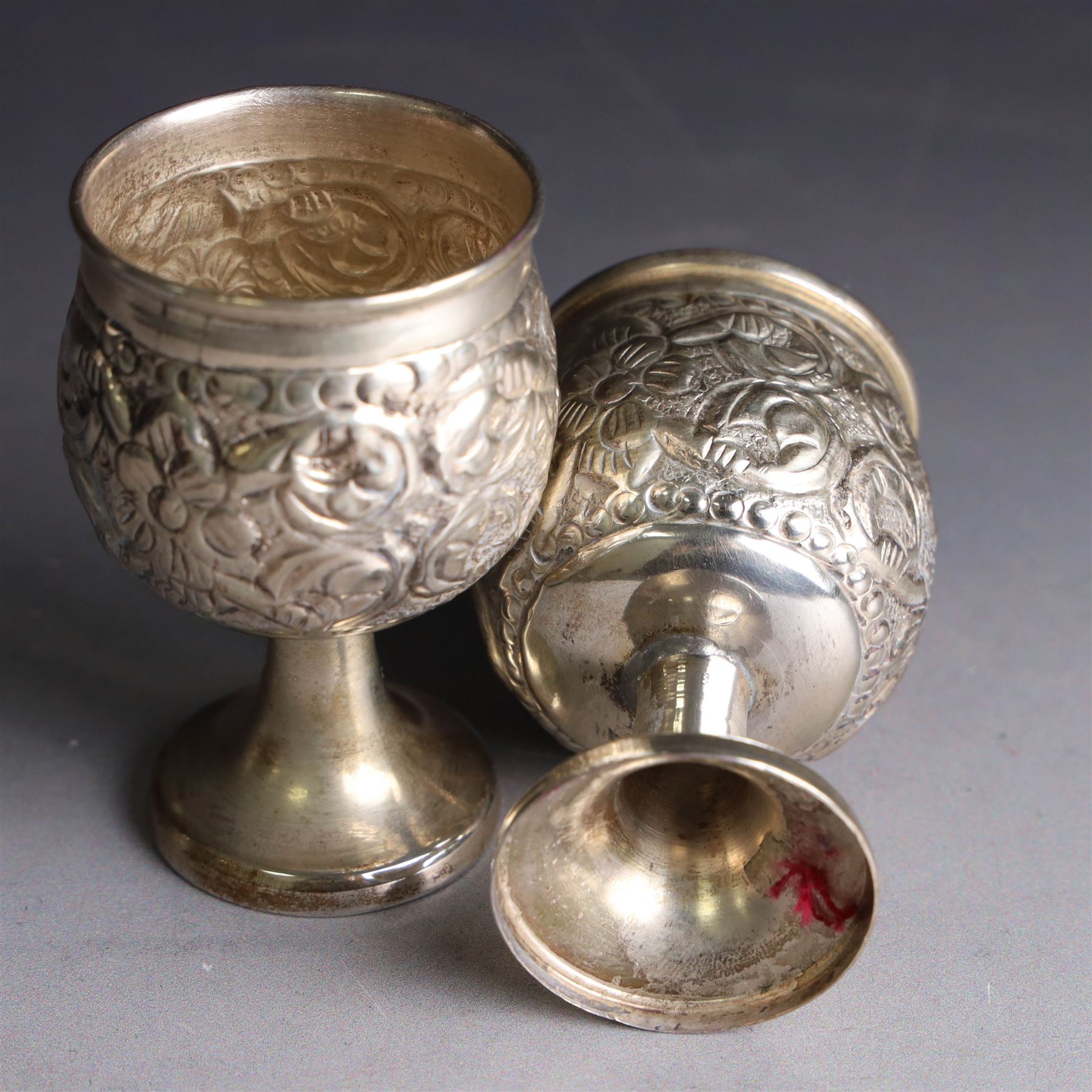 Pair of miniature Indian silver goblets, with embossed floral and foliate decoration, H6.5cm