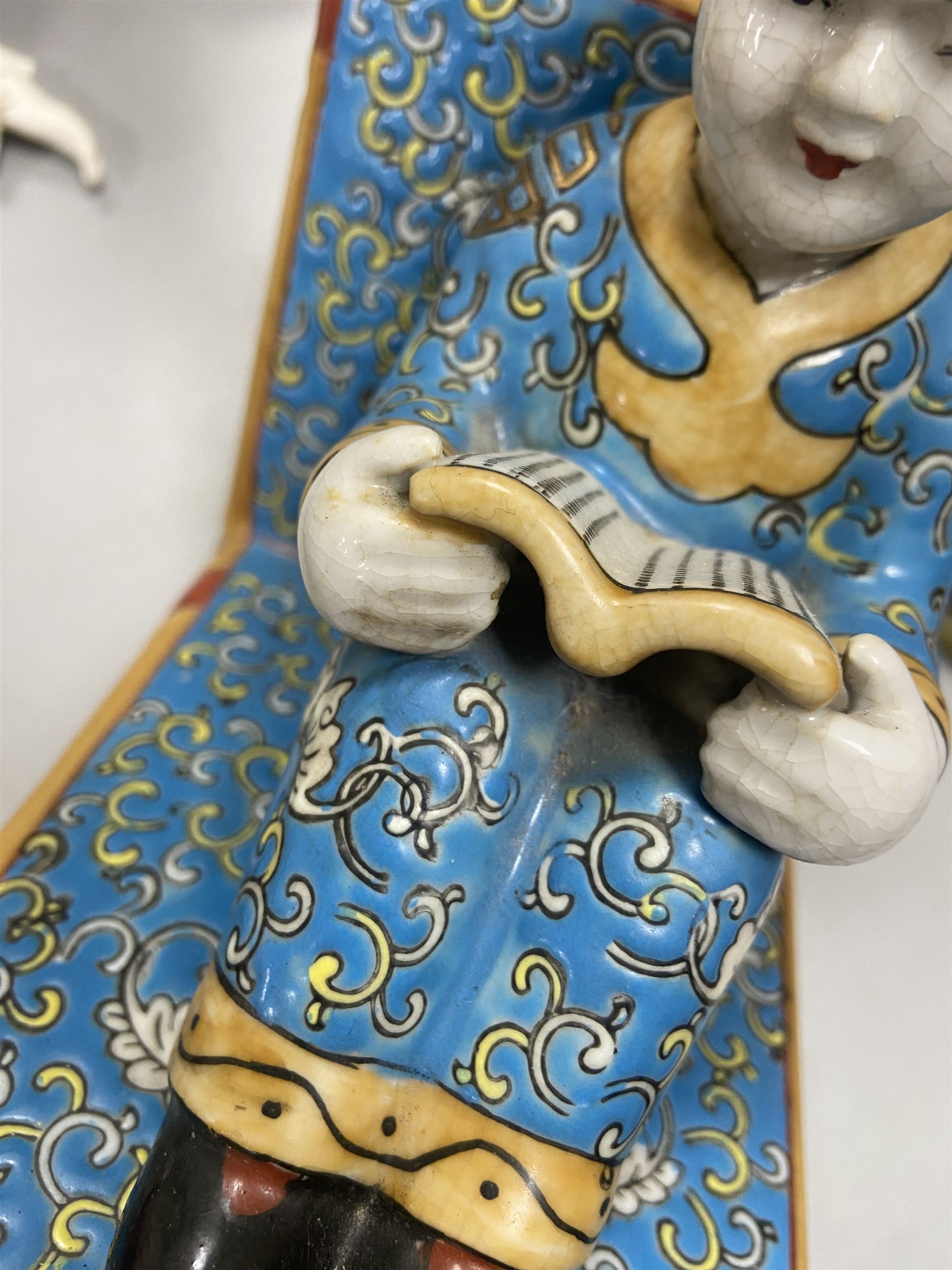 Pair of 20th century Chinese figural bookends, modelled as children in traditional blue dress sat reading and kneeling upon stacks of books, H22cm