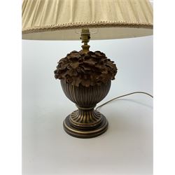 A composite wood effect table lamp, the reeded bulbous body detailed with oak leaves and acorns, upon spreading circular base, with pleated beige fabric shade, overall H58.5cm.