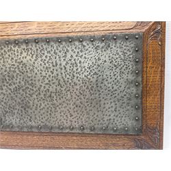 Arts and Crafts oak stand by Arthur Simpson of Kendal, of rectangular form with central hammered pewter panel, surrounded by a border with carved foliate corners, upon two bar supports, bearing label detailed 