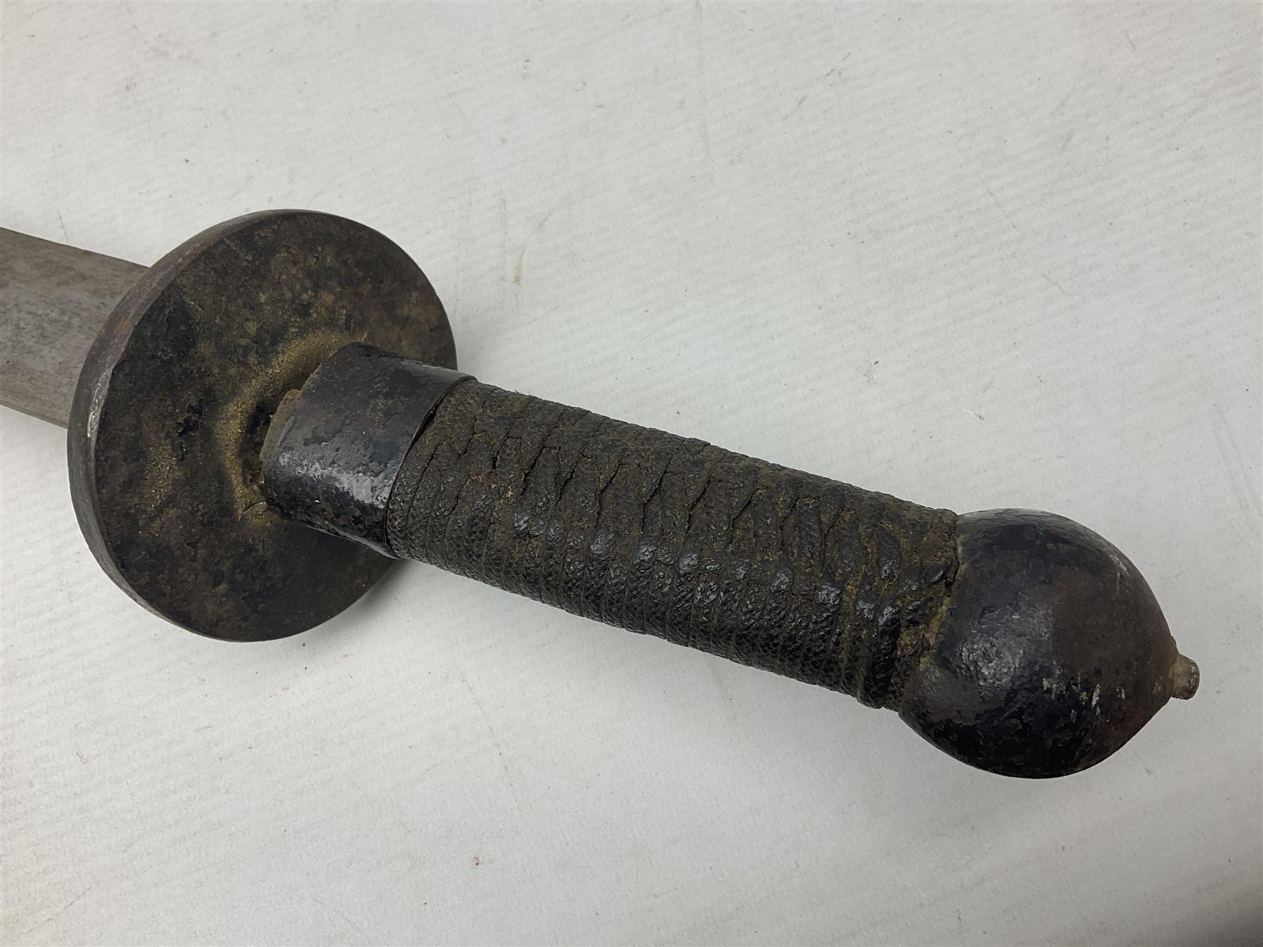 Chinese Boxer Rebellion Period Sword, 69.5cm heavy curved single edge blade with single narrow fuller, plain iron dished circular guard, iron pommel and ferrule with plaited cord bound grip; in skin covered wooden scabbard with iron chape and long suspension mount L95cm overall