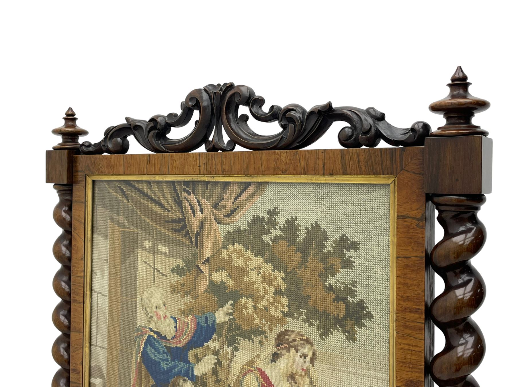 Victorian rosewood fire screen, scrolled foliage carved pediment, rectangular frame with moulded gilt slip enclosing figural needlework tapestry panel, on spiral turned supports with finials united by turned lower stretcher, on out-splayed feet with scroll carved terminals 