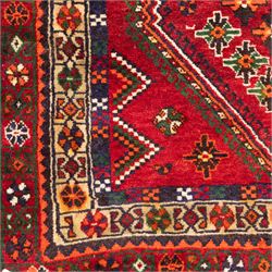 South West Persian Lori hand-knotted rug,  deep crimson field with a stepped lozenge medallion enclosing stylised floral motifs within multiple geometric borders of indigo, ivory, and green, with fringe ends 