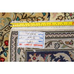 Central Persian Kashan hand-knotted carpet, ivory ground with a central floral medallion with an all-over design of scrolling vinery, palmettes, and flowering sprays i tones of madder red, cobalt, navy blue and sage green, with conforming spandrels, main border of deep indigo ground with repeating palmettes and stylized floral heads, flanked by narrow guard stripes, with cotton fringe ends, with cotton fringe ends 