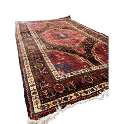 Persian Hamadan red and blue ground rug, the field with extending lozenge decorated with small stylised flower head motifs, the spandrels decorated with tree of life motifs, within a multi-band border with overall geometric design