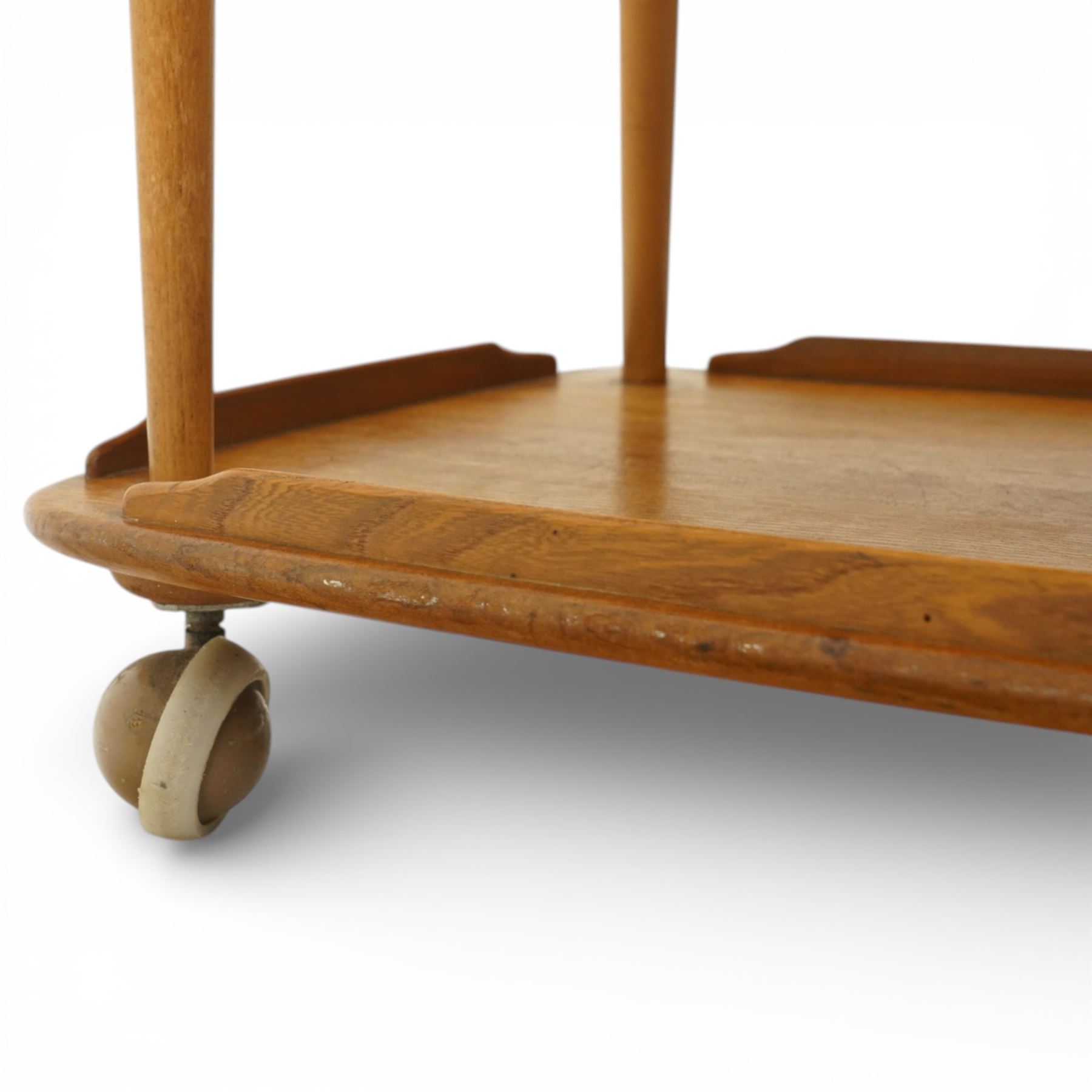 Ercol - elm tea trolley, Model 458. Rectangular three-tier form with shaped gallery edges, supported on turned upright supports, raised on castors