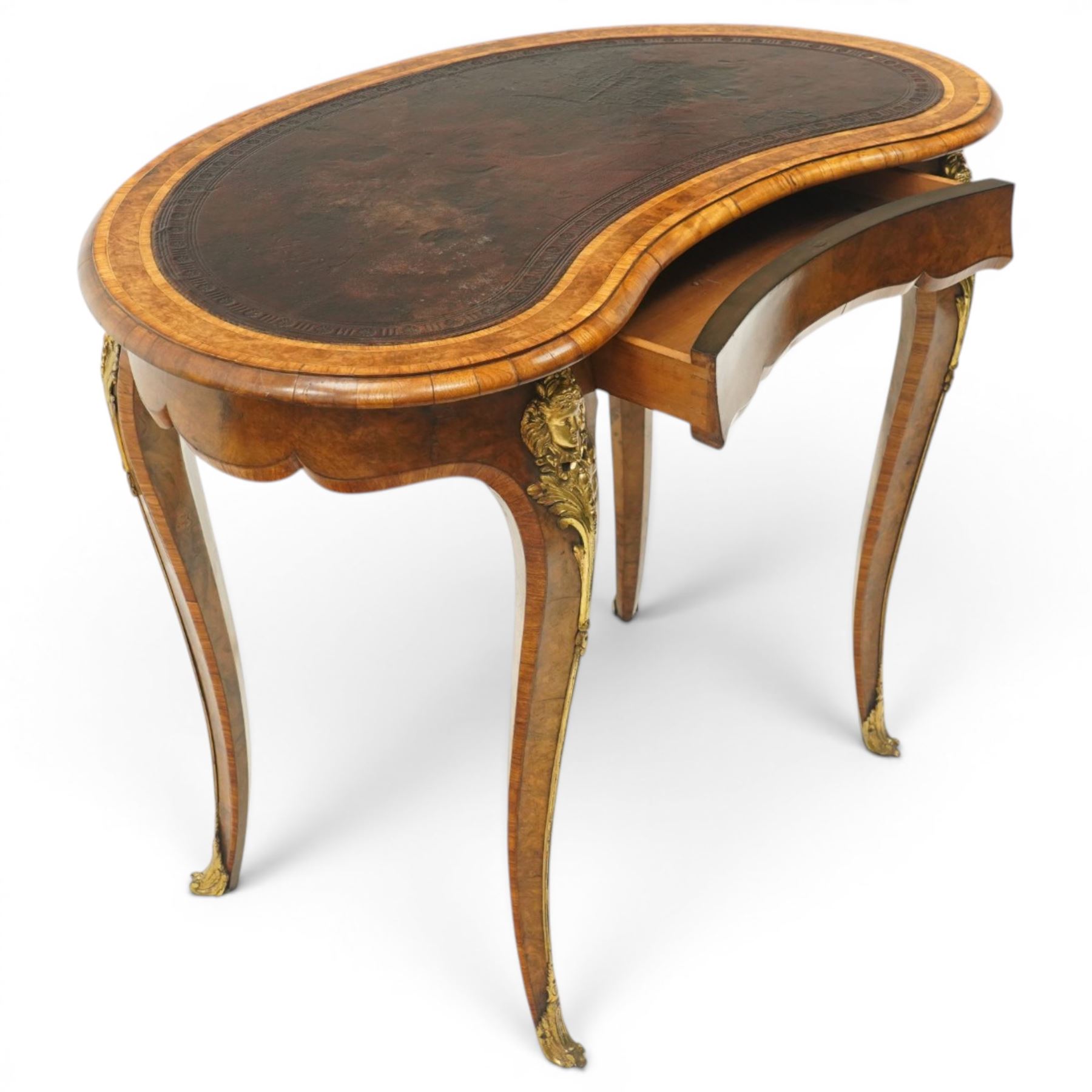 Gillow & Company (1862-1897) - Victorian figured walnut kidney shaped writing table, the shaped top inset with oxblood leather writing surface with embossed edge, surrounded by banded burr-walnut and crossbanding with moulded edge, fitted with single shaped frieze drawer flanked by scalloped side-aprons, raised on tapering and chamfered cabriole supports embellished with ormolu mounts in the forms of maidens over tapering acanthus leaves, the mounts trailing down the front of the legs to terminate to ormolu scroll feet, stamped 'Gillow & Co 3576' to drawer interior