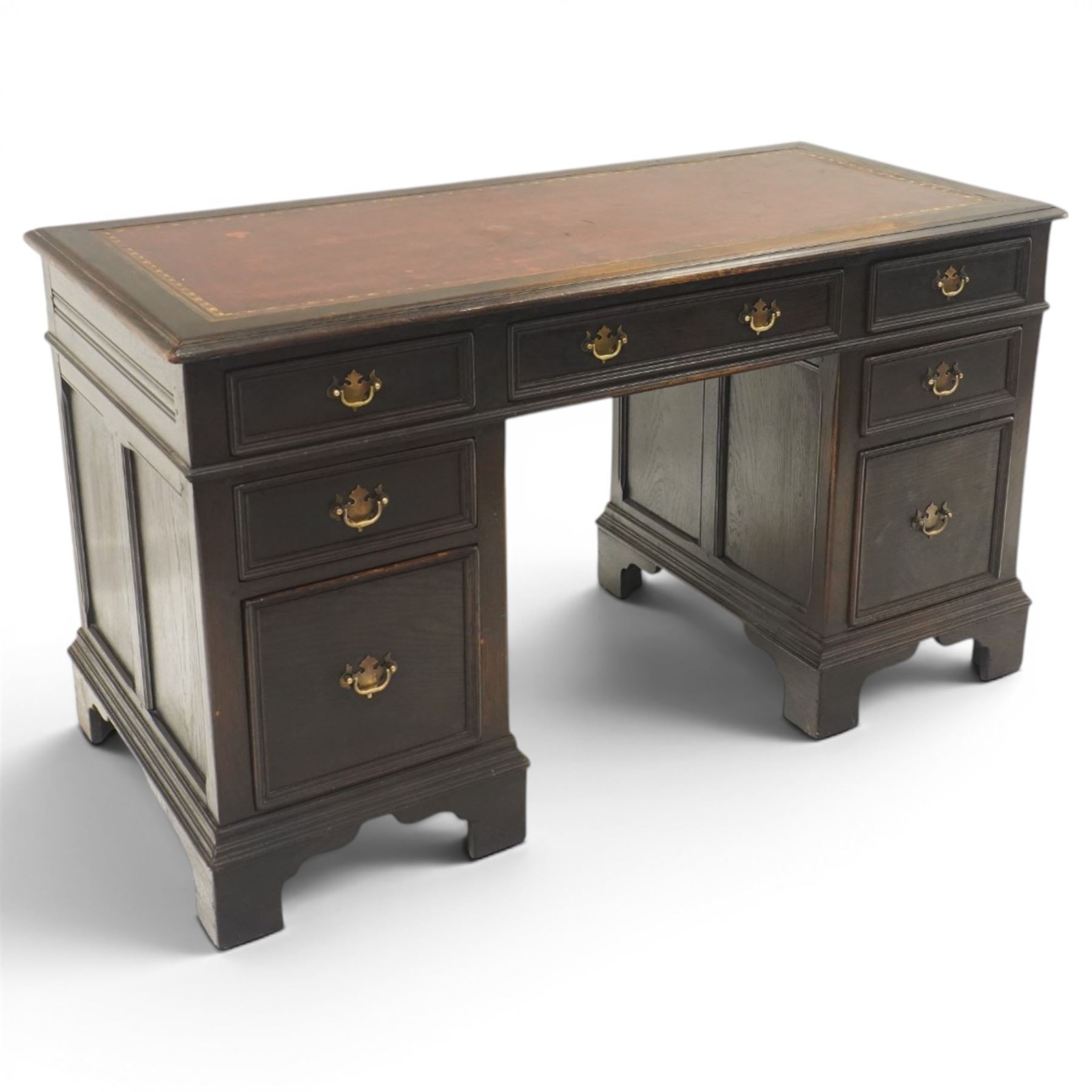 Titchmarsh & Goodwin style desk, rectangular top with inset red leather writing surface, central frieze drawer flanked by three drawers, pedestals fixed to the top, raised on bracket feet 