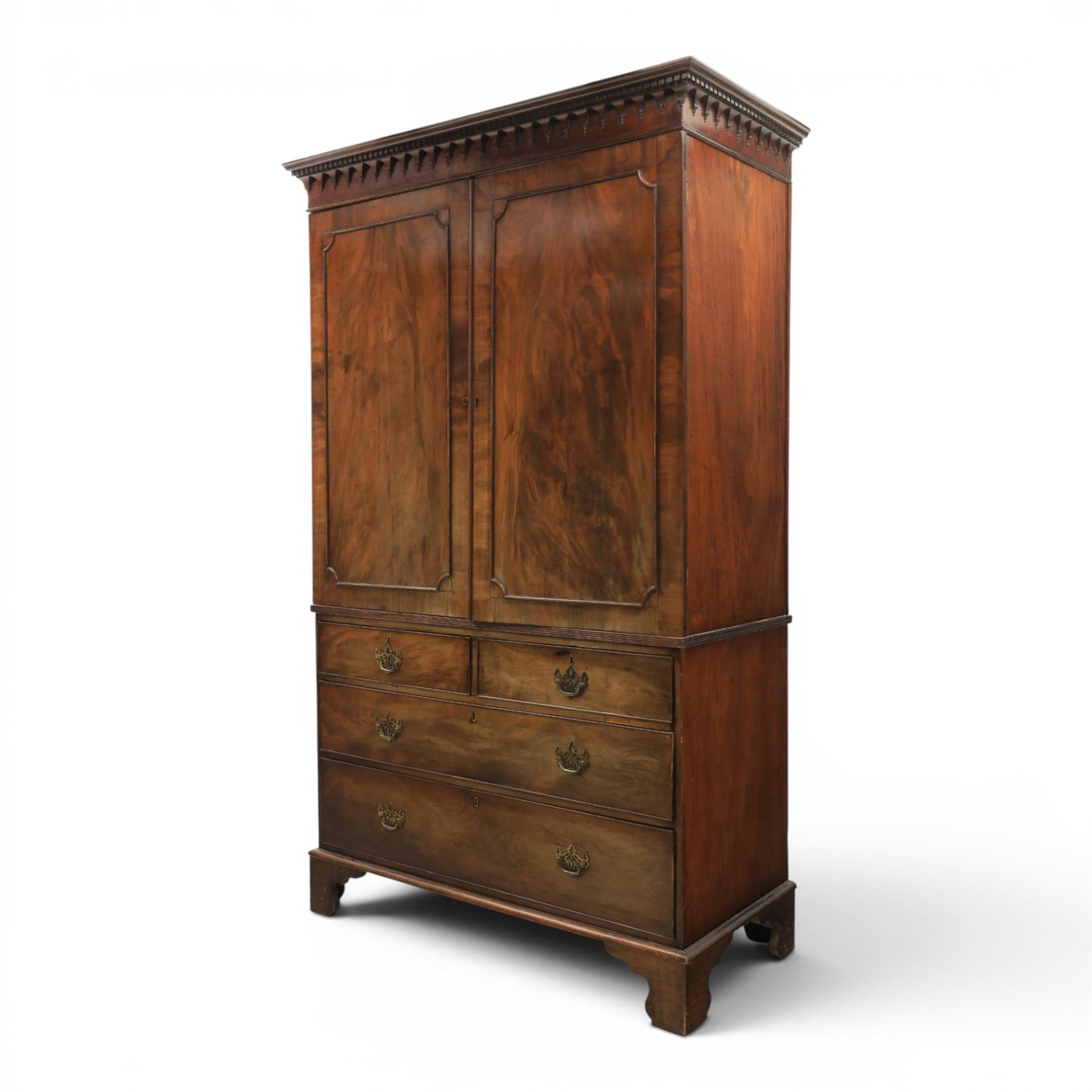 George III mahogany linen press, projecting dentil cornice, moulded doors enclosing a shelved interior, above a lower section with two short over three long drawers, raised on bracket feet 