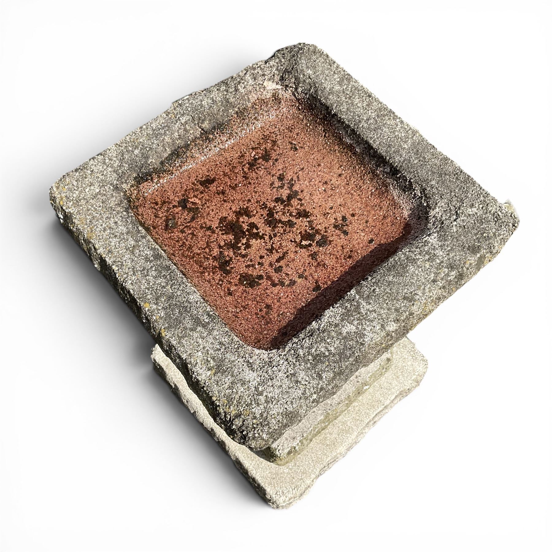 Early 20th century composite three-piece stone birdbath, square dished top on tapering pedestal and stepped base