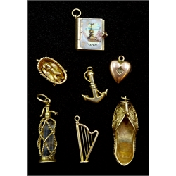 Seven 9ct gold charms including a soda siphon, baby in a basket, harp, Indian shoe and a book, hallmarked or tested