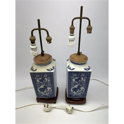 A pair of blue and white table lamps, of square sectional form decorated with dragons, prunus blossom, bats and a key fret border, each upon wooden base, overall H66cm. 