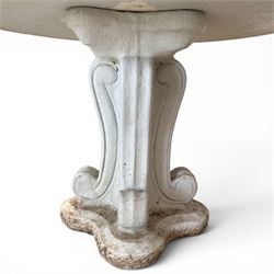 Weathered cast stone garden table, circular top etched with central floral medallion, the edge with repeating chevron motifs, raised on a quadriform S-scroll pedestal with stepped and chevron carved base