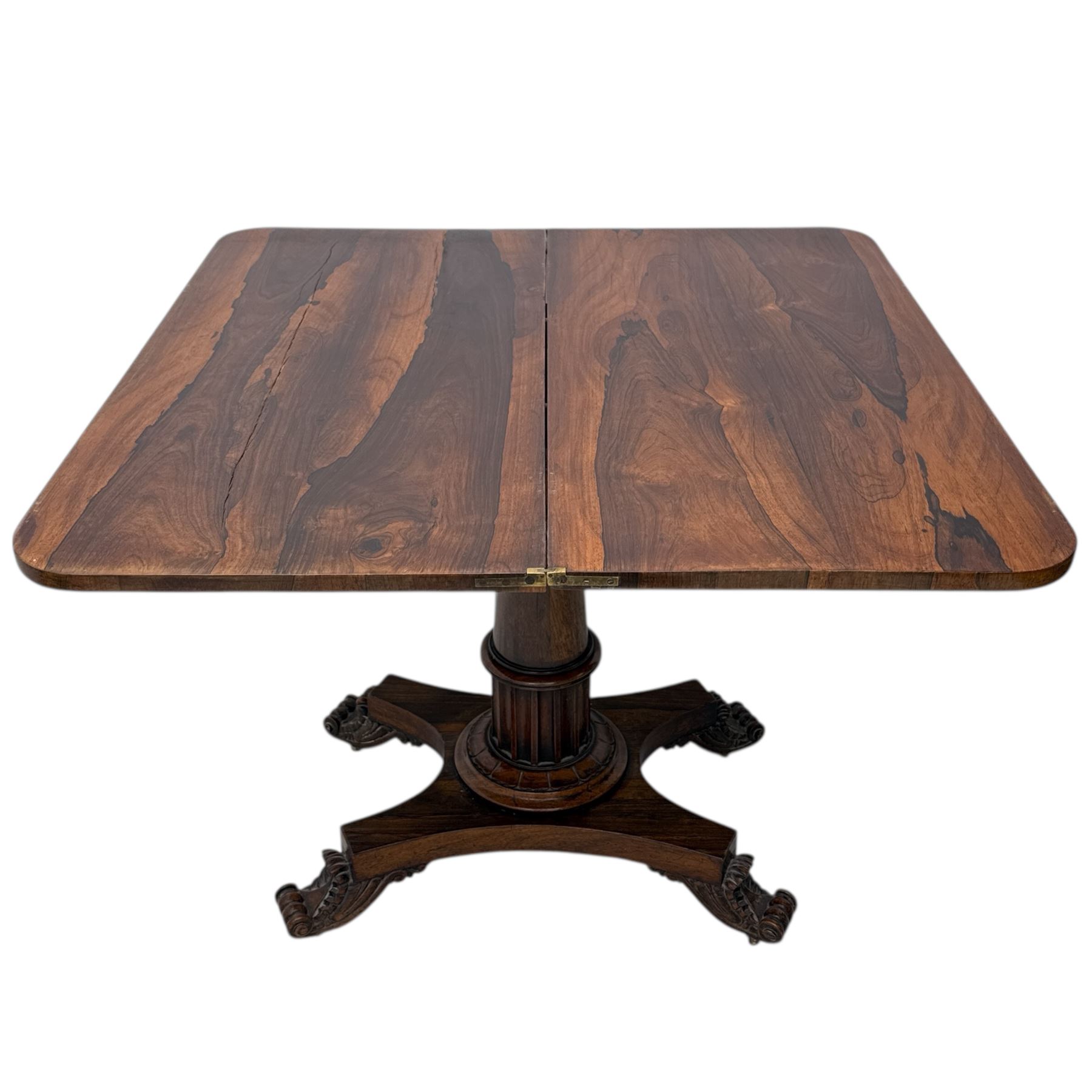 William IV rosewood card table, rounded rectangular swivel and fold-over top with plain frieze, with carved scrolled brackets above stop-fluted column with moulded collar on quadriform base with scrolled feet 