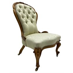 Victorian walnut framed nursing chair, the cresting rail decorated with carved applied flower heads and acanthus leaves, shaped back and sprung seat upholstered in buttoned ivory damask fabric, serpentine front over cartouche carved cabriole supports with ceramic castors (W57cm H92cm); with matched footstool, circular top over shaped moulded apron, on floral carved cabriole feet (W34cm) 