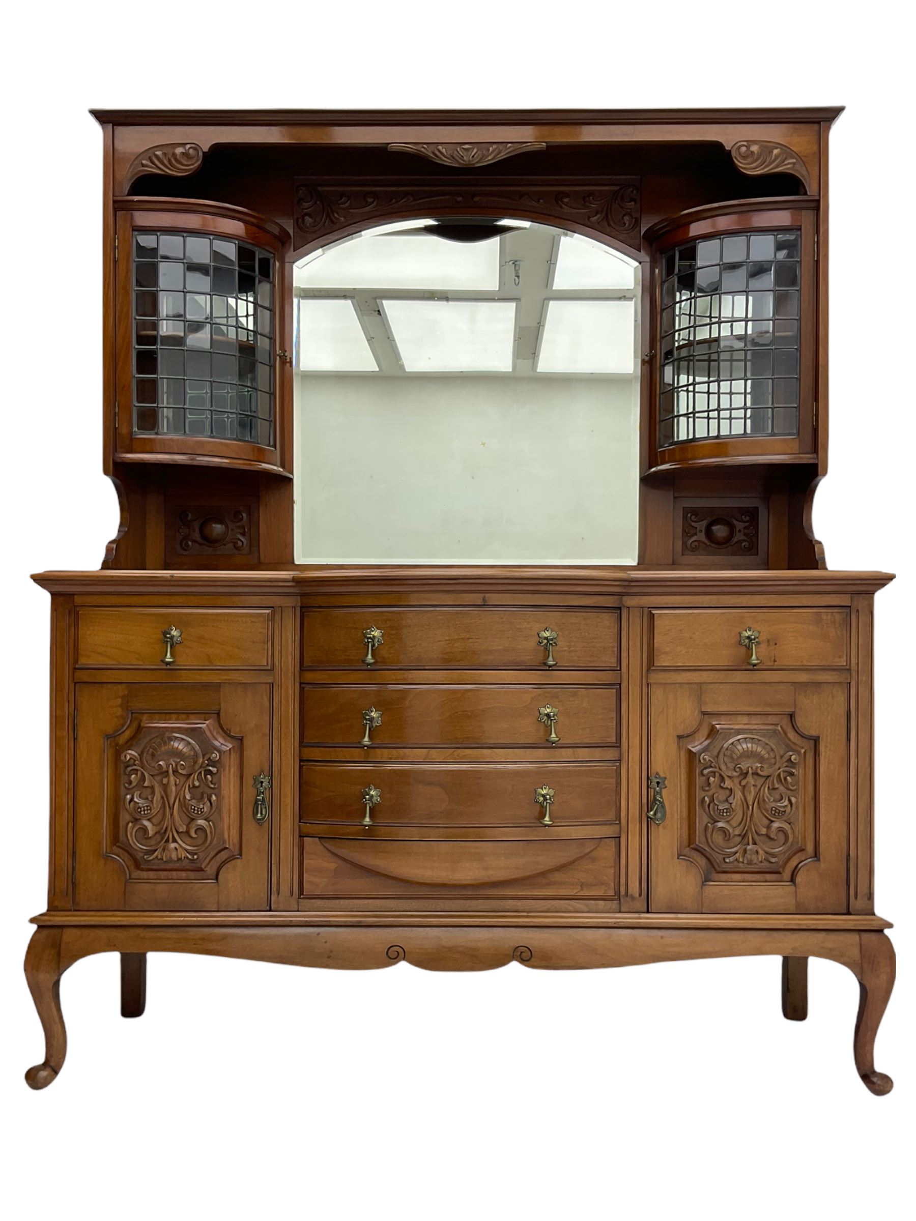 Late Victorian walnut mirror back sideboard or dresser, the raised back fitted with two curved and lead glazed cabinets, central arched bevelled mirror, the sideboard with break bowfront, fitted with six drawers and two cupboards, the cupboard doors panelled and carved with scrolls, shell and plant motifs, shaped apron with cabriole feet
