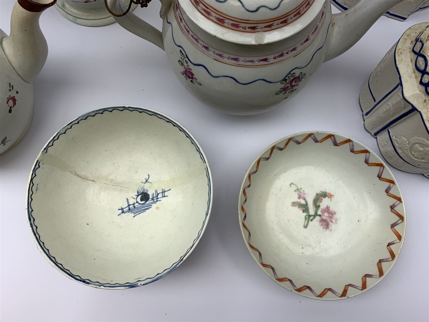Two19th century relief moulded Castleford teapots, and lidded sucrier, largest teapot H14.5cm, together with three 18th century New Hall type teapots, an early 18th century saucer, and an 18th century blue and white bowl.