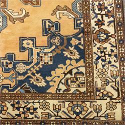 North West Persian Tafresh hand-knotted rug, pale apricot field with central stepped medallion enclosing stylized floral and angular motifs framed by indigo spandrels and multiple stylized floral borders, cotton fringe ends 
