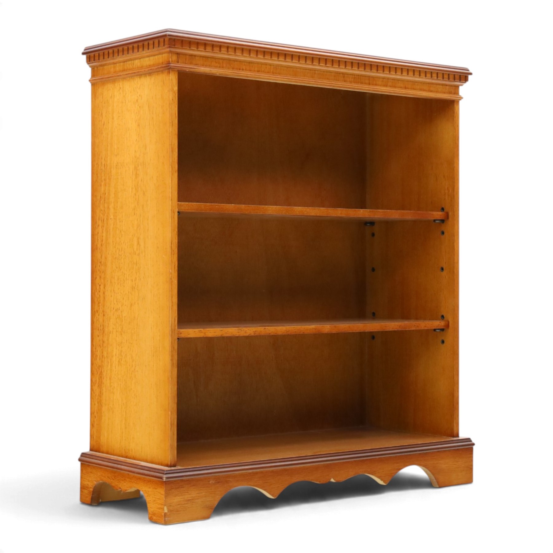 Contemporary mahogany and yew wood open bookcase, dentil cornice above two adjustable shelves, shaped apron and bracket feet 
