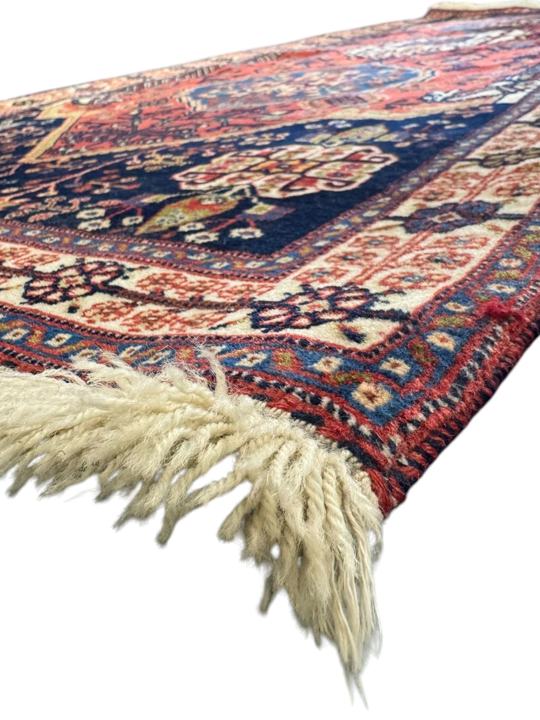 Fine Persian Qashqai crimson and navy ground runner, three large medallions filled with geometric and floral designs, the field with angular vines and stylised floral decoration, wide ivory border decorated with repeating floral and angular motifs