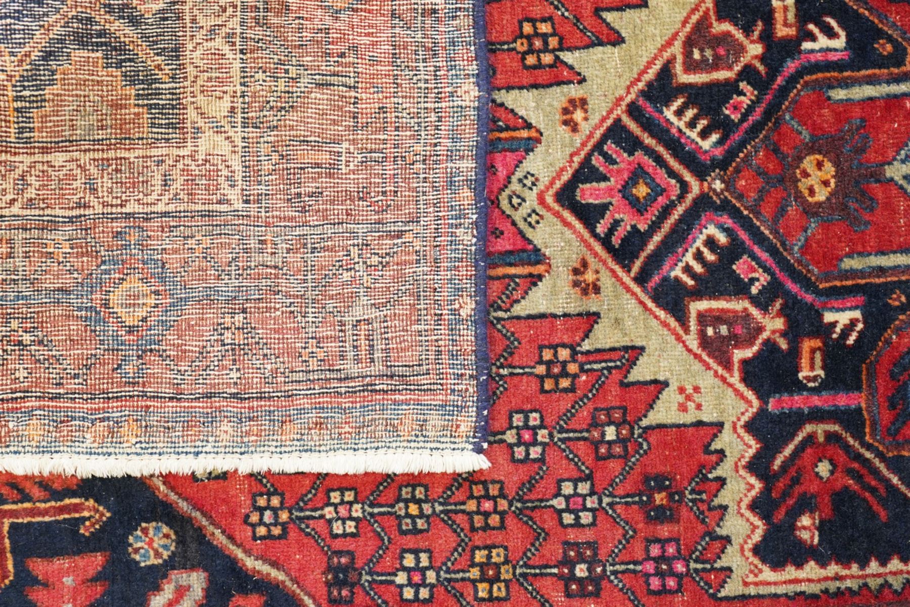 Persian Hamadan crimson ground rug, the indigo field decorated with a central geometric medallion, filled and surrounded by stylised plant motifs, the guard bands with further geometric decoration