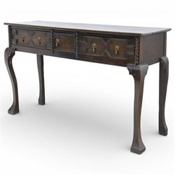 Late 19th century Jacobean revival oak side table, plank top with moulded edge over a central cupboard door and two frieze drawers carved with geometric lozenge motifs and framed by bobbin turned uprights, fitted with brass drop handles, raised on shaped cabriole supports with block feet
