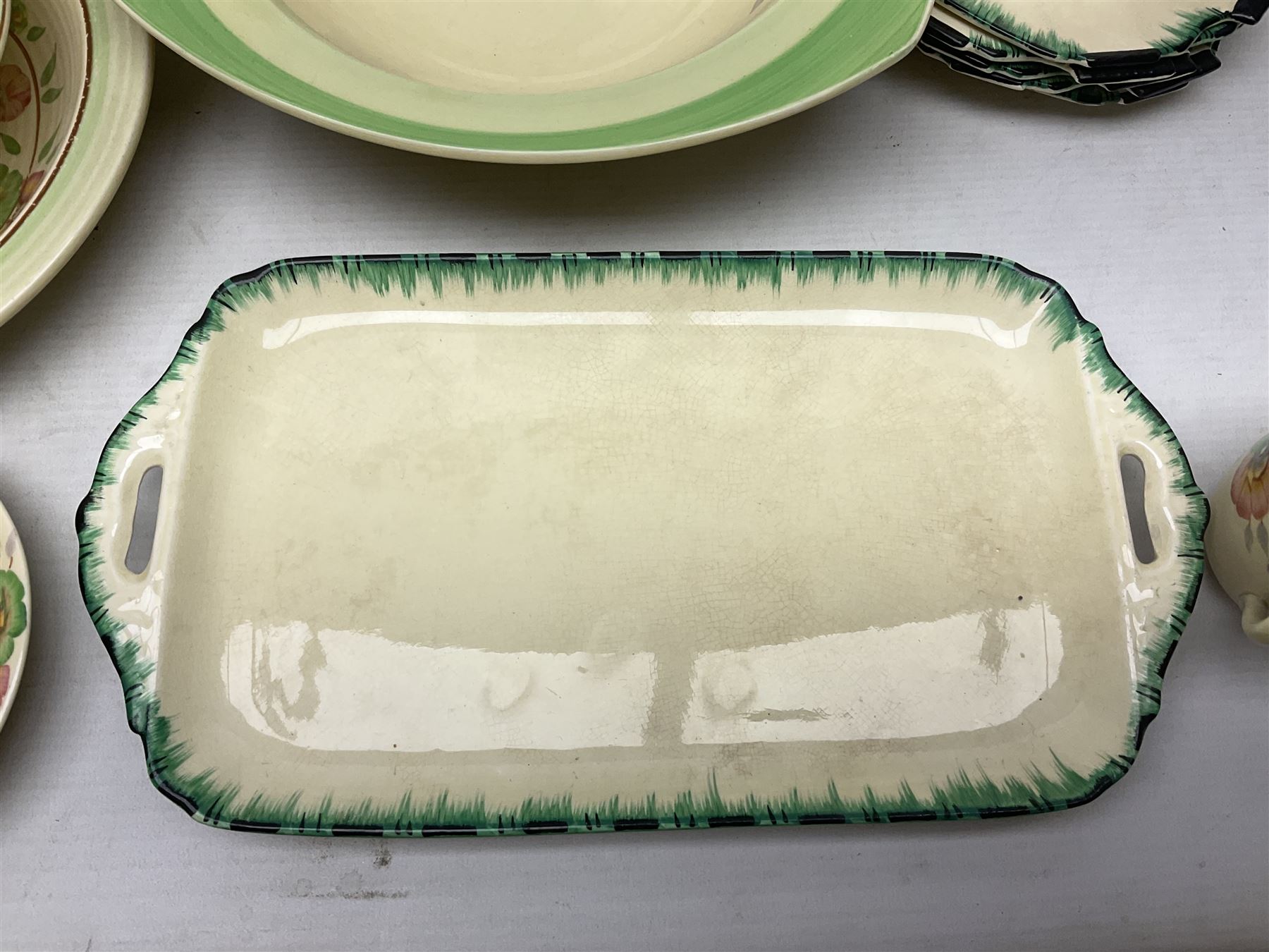 Clarice Cliff for Newport Pottery Corolla pattern tea and dinner wares, comprising triangular bowl, four side plates, two shallow bowls and teacup (a/f), together with a Clarice Cliff Wilkinson twin handled soup bowl and unassociated saucer both decorated with pink and yellow flowers, together with other mid century ceramics comprising Parrott and Company Coronet Ware, and Royal Staffordshire AJ. Wilkinson Ltd dinner wares