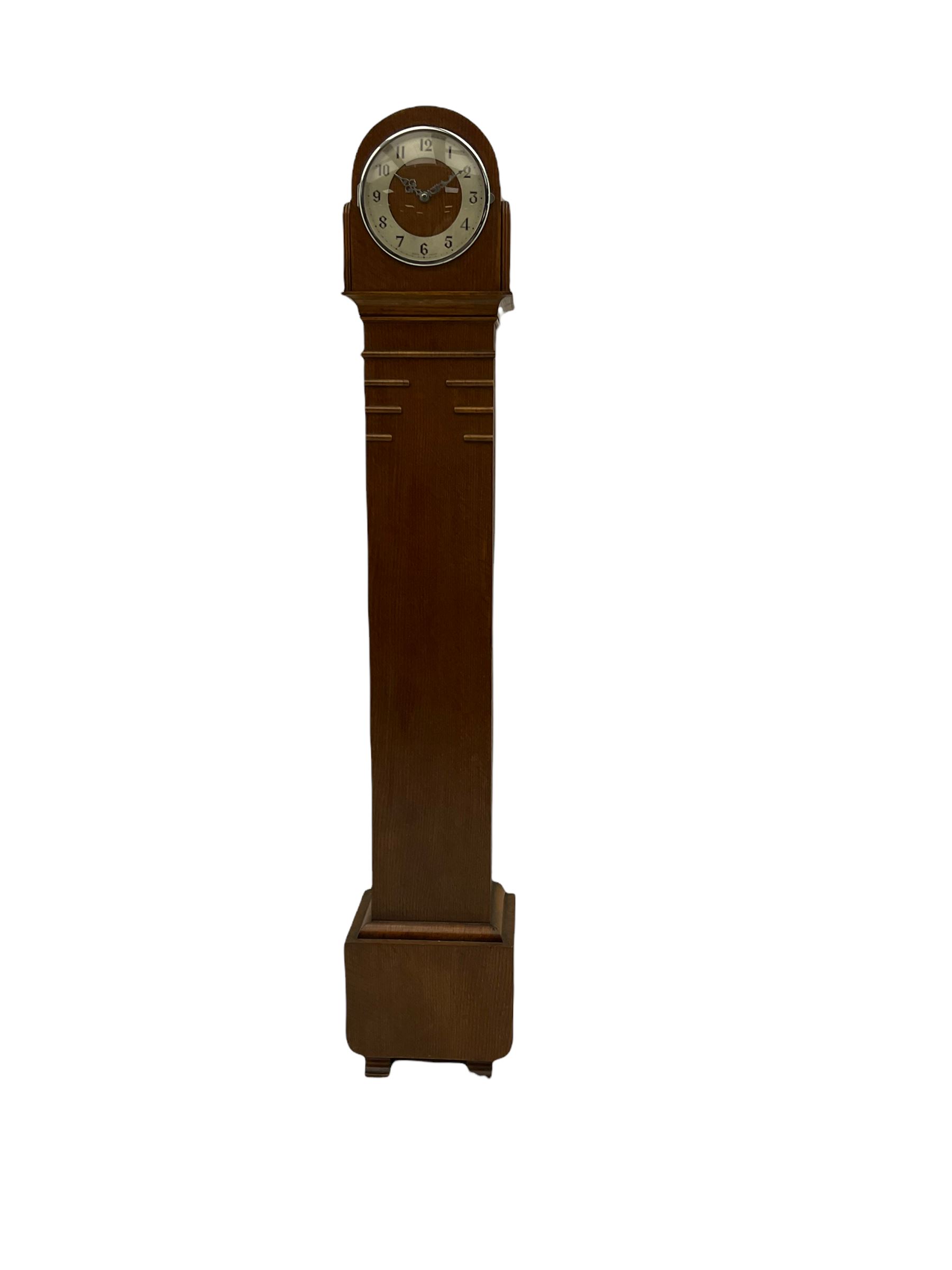 A mid-20th century English art-deco Grandmother clock with a mains powered electric movement chiming the hours and quarters on gong rods, in an oak case with an arched top, long trunk and short plinth on bracket feet, sliver effect chapter ring with Arabic numerals and silvered serpentine hands, with chime/silent facility.



